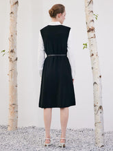 A lady is standing with her back turned in a shift dress.